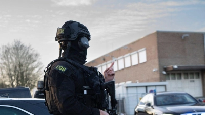 Maskierte und bewaffnete niederländische Polizisten bewachen einen Transport mit einigen der Verdächtigen, die vor dem Hochsicherheitsgebäude des Gerichts in Amsterdam eintreffen. (Foto: Peter Dejong/AP/dpa)