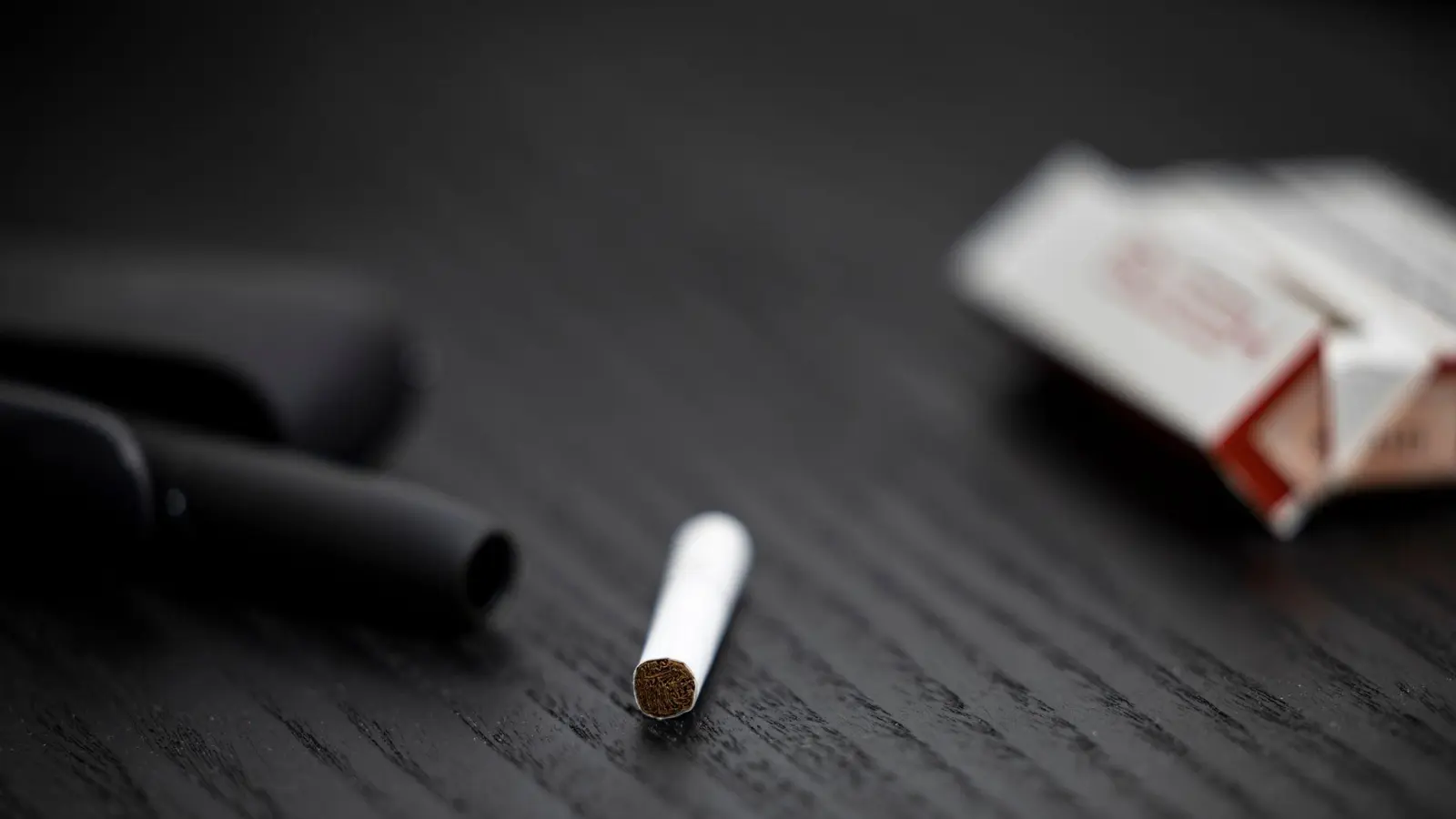 Ein Tabakstick, Stickpäckchen und Tabakerhitzer liegen auf einem Tisch. Die drei Branchenriesen haben hohe Erwartungen an den künftigen Absatz. (Foto: Hannes P. Albert/dpa)
