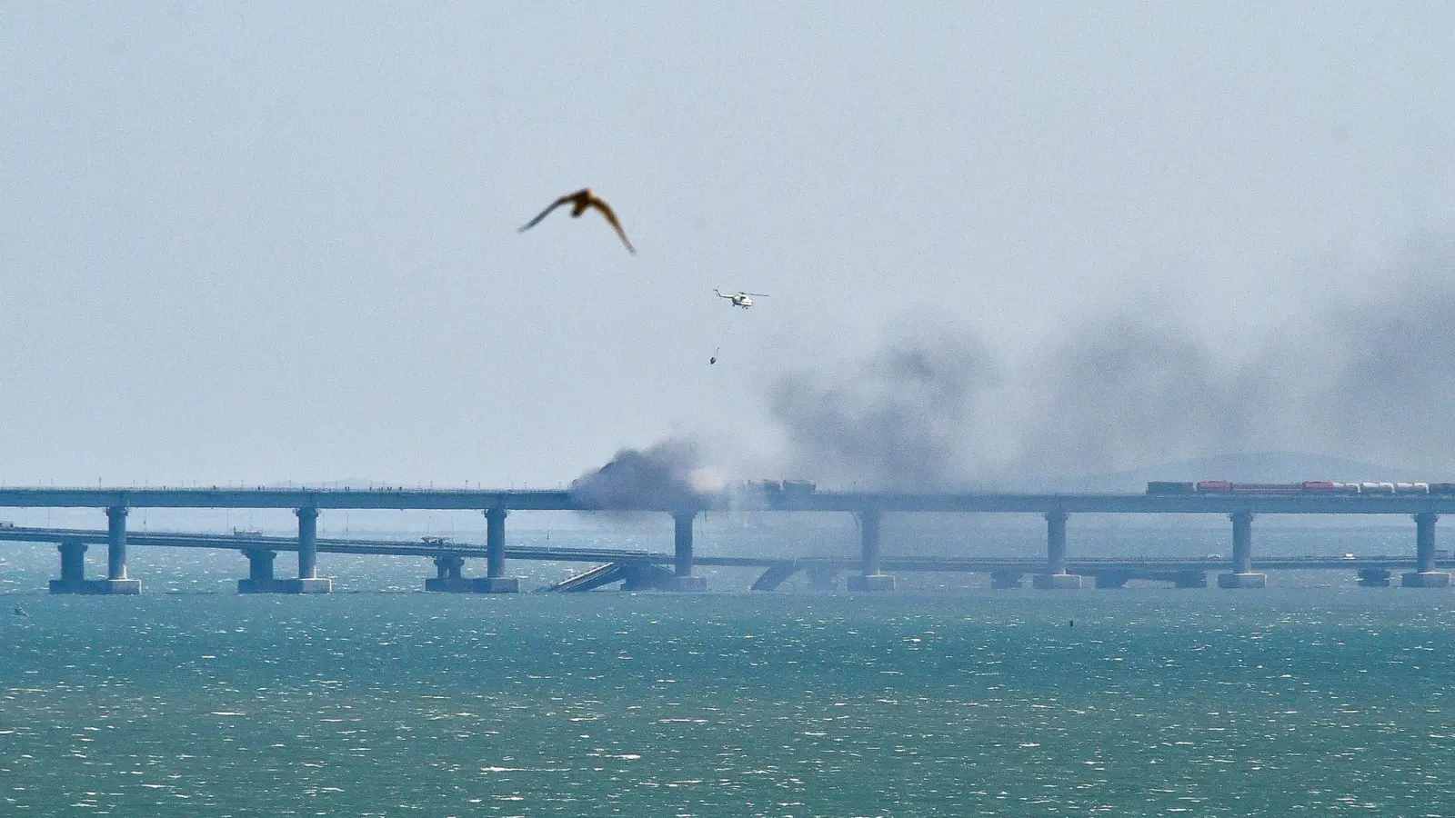 Ein Hubschrauber wirft Wasser ab, um das Feuer auf der Krim-Brücke zu löschen. (Foto: Uncredited/AP/dpa)