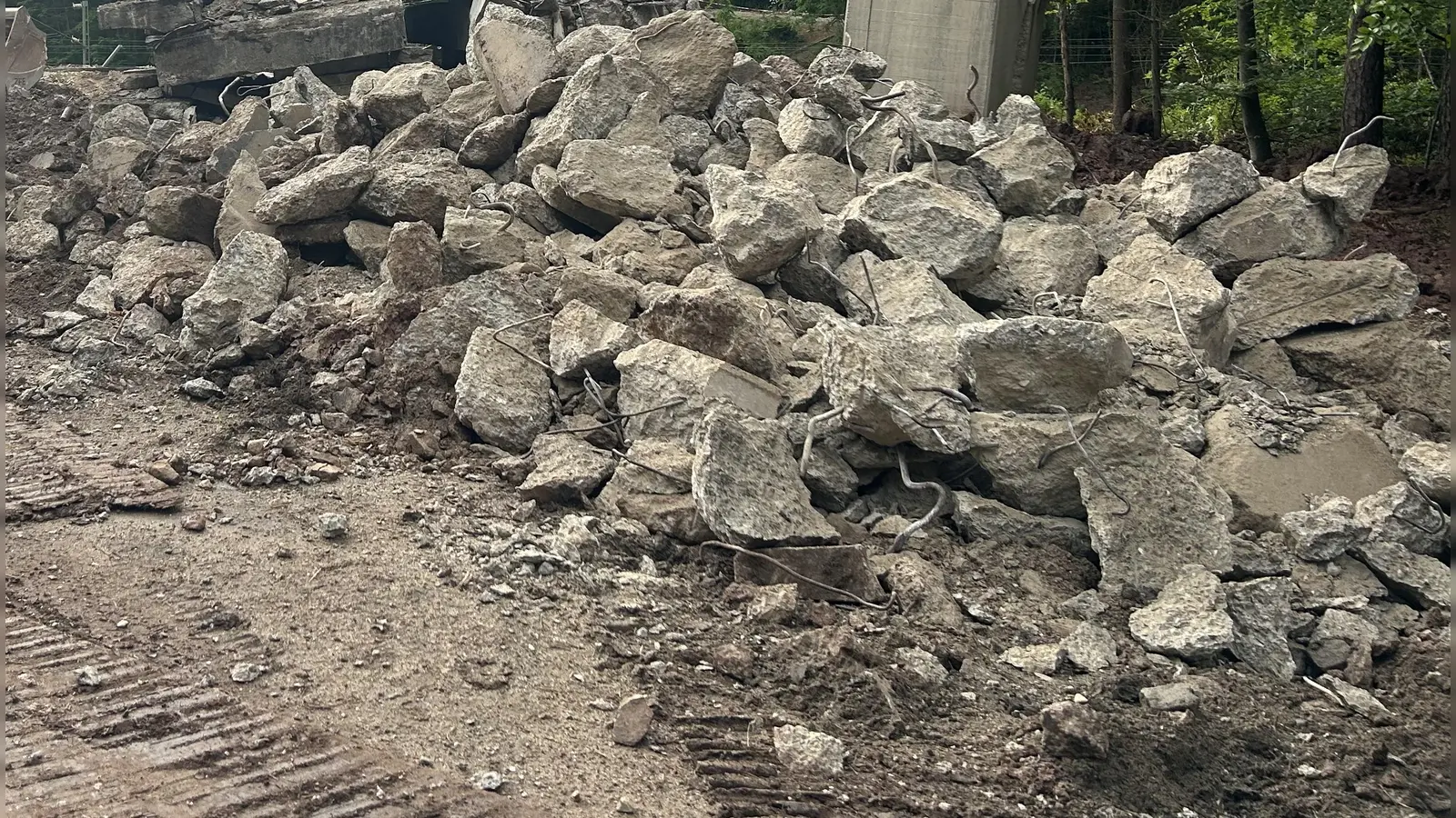 Große Betonteile lagern derzeit auf der Petersauracher Seite der ehemaligen Brücke. Ein Spezialunternehmen ist gerade dabei, die tonnenschweren Stücke zu zerkleinern. (Foto: Florian Pöhlmann)