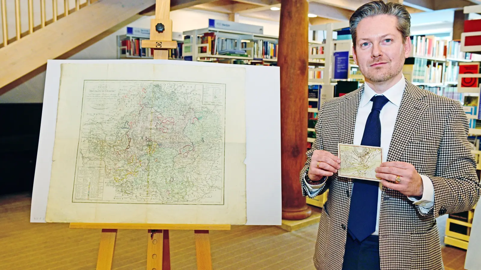 Die große „Charte von dem Fränkischen Kreise“ von 1804 gehört zu den restaurierten Karten. Bibliotheksleiter Christian Mantsch zeigt noch eine kleine Karte mit der Schlacht von Landau 1713. (Foto: Jim Albright)