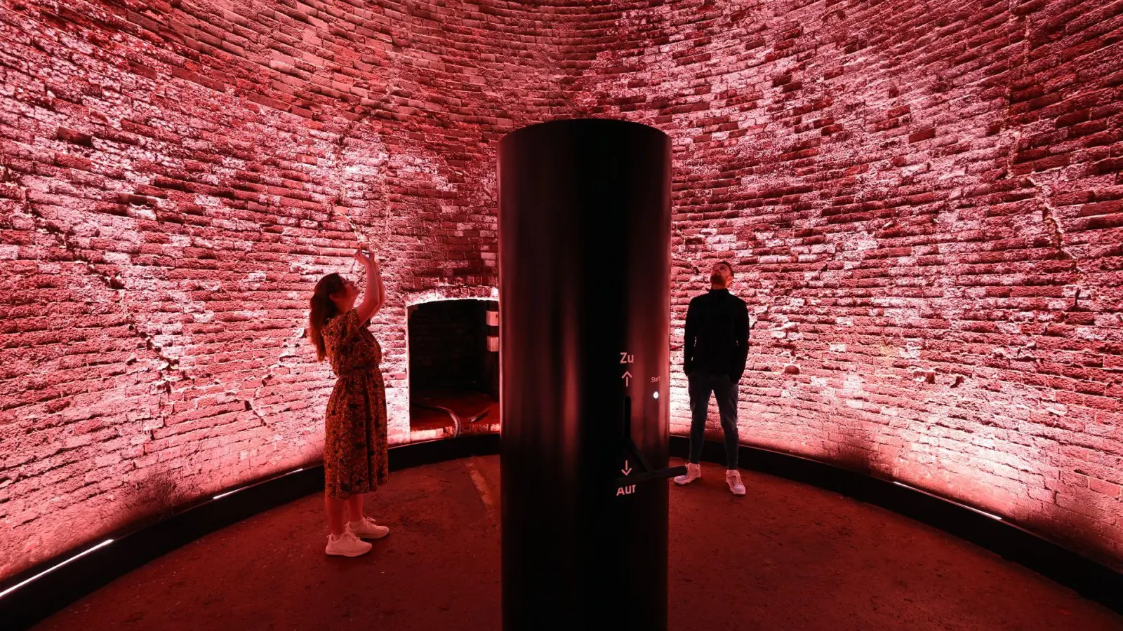 Höllenmaschine mit Lichtkunst: Der 98 Meter hohe Schornstein der Kokerei Zollverein leuchtet rot als Teil des erweiterten Denkmalpfads. (Foto: Federico Gambarini/dpa/dpa-tmn)