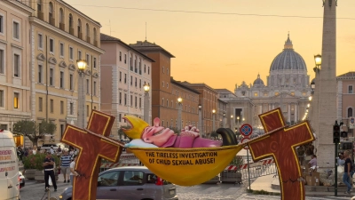 Einer Figur des Künstlers Jacques Tilly, die ironisch die Kirche für ihre Missbrauchsermittlungen kritisiert, steht in Rom in Sichtweite des Petersdoms. (Foto: Ricarda Hinz/dpa)