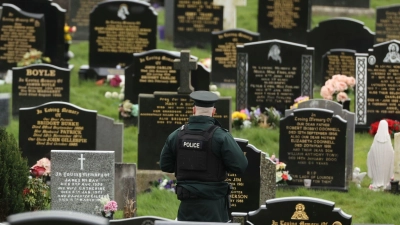 Ein PSNI-Polizist patrouilliert auf dem Stadtfriedhof von Londonderry. Kurz vor der Ankunft von US-Präsident Biden in Nordirland fand die Polizei dort vier mutmaßliche Rohrbomben. (Foto: Liam Mcburney/PA Wire/dpa)