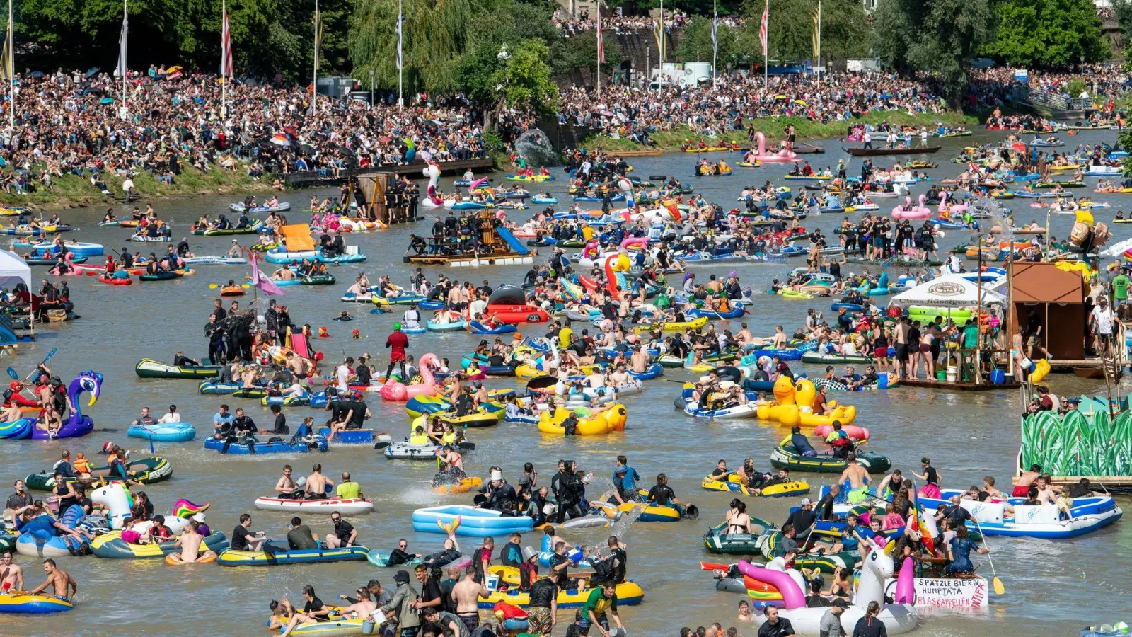 Unzählige Schlauchboote treiben den Fluss hinab, während noch mehr Schaulustige entlang des Ufers mitfeiern. (Foto: Stefan Puchner/dpa)