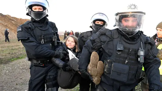 Polizisten tragen die schwedische Klimaaktivistin Greta Thunberg aus einer Gruppe von Demonstranten und Aktivisten heraus vom Rand des Braunkohlentagebaus Garzweiler II weg. (Foto: Roberto Pfeil/dpa)
