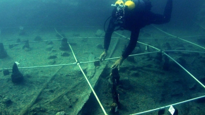 Ein Kanu wird Boden des Braccianosees ausgegraben. Die abgenutzten Überreste der mehr als 7000 Jahre alten Kanus lassen erahnen, wie ausgeprägt das Wissen über die Seefahrt bereits in der Jungsteinzeit war. (Foto: Gibaja Et Al/2024, Plos One, C/dpa)
