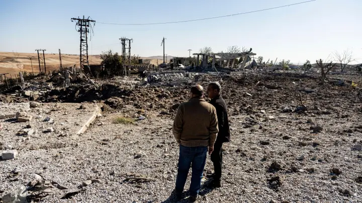 Zwei Männer begutachten Schäden in einem Gebiet um ein Elektrizitätswerk in Nordsyrien nach türkischen Luftangriffen. (Foto: Baderkhan Ahmad/AP/dpa)