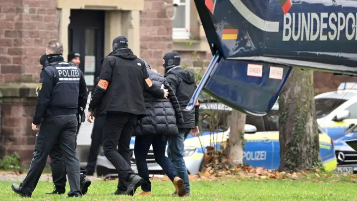 Eine Person wird in Karlsruhe von Polizisten aus einem Hubschrauber gebracht: Alle bei der Razzia am 7. Dezember festgenommenen Beschuldigten sind weiterhin in Haft. (Foto: Uli Deck/dpa)