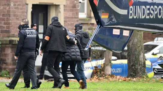 Eine Person wird in Karlsruhe von Polizisten aus einem Hubschrauber gebracht: Alle bei der Razzia am 7. Dezember festgenommenen Beschuldigten sind weiterhin in Haft. (Foto: Uli Deck/dpa)