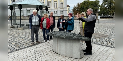 Viele Touristen lassen sich bei einer Führung – hier mit Historiker Alexander Biernoth (rechts) am Bronze-Tastmodell der Stadt auf dem Schlossplatz – die Geheimnisse Ansbachs erklären. (Archivbild: Oliver Herbst)