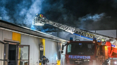 Mitarbeiter der Feuerwehr löschen einen Brand in einer Asylbewerberunterkunft. (Foto: Marius Bulling/dpa)