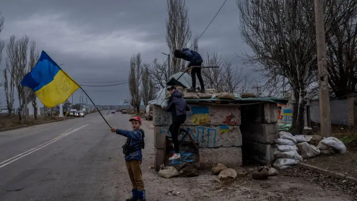 Ukrainische Kinder spielen an einem verlassenen Kontrollpunkt in Cherson. (Foto: Bernat Armangue/AP/dpa)
