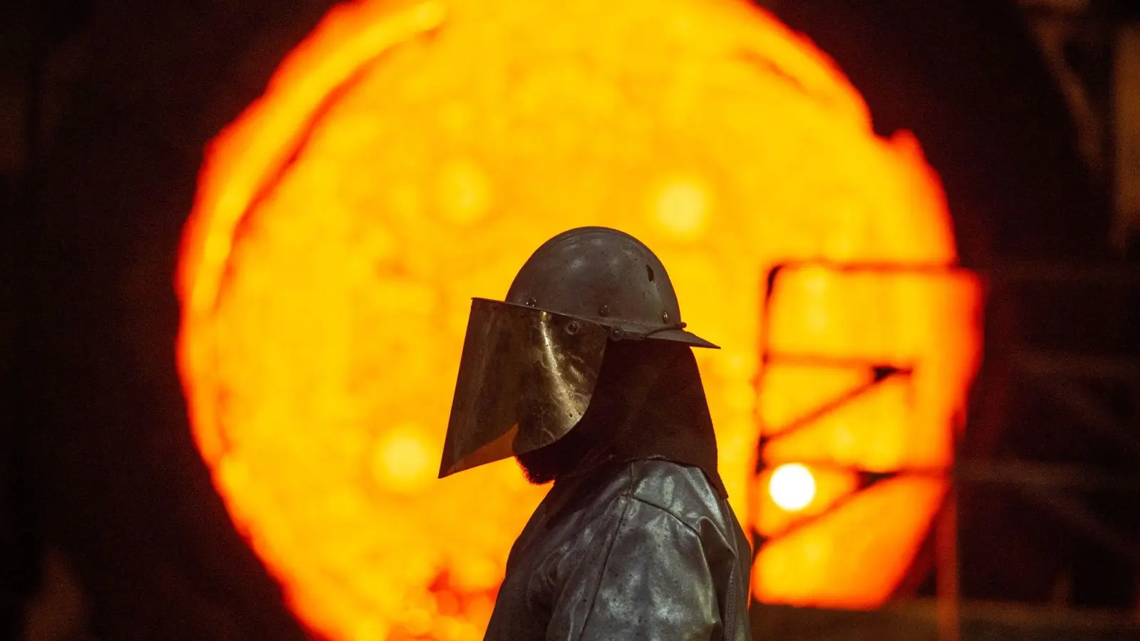 Ein Mitarbeiter steht im Stahlwerk der Salzgitter AG vor einer glühenden Roheisenpfanne. (Foto: Christophe Gateau/dpa)