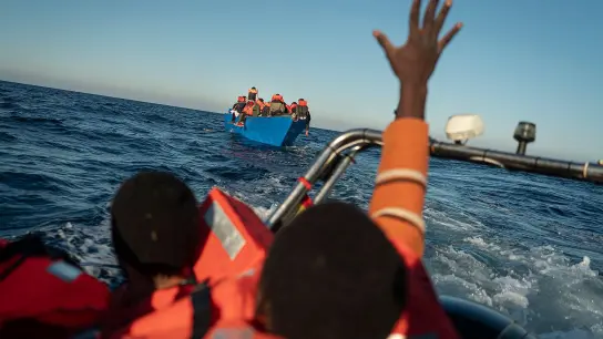 Migranten und Flüchtlinge treiben auf einem überfüllten Holzboot im Mittelmeer (Symbolbild). (Foto: Pau De La Calle/AP/dpa)