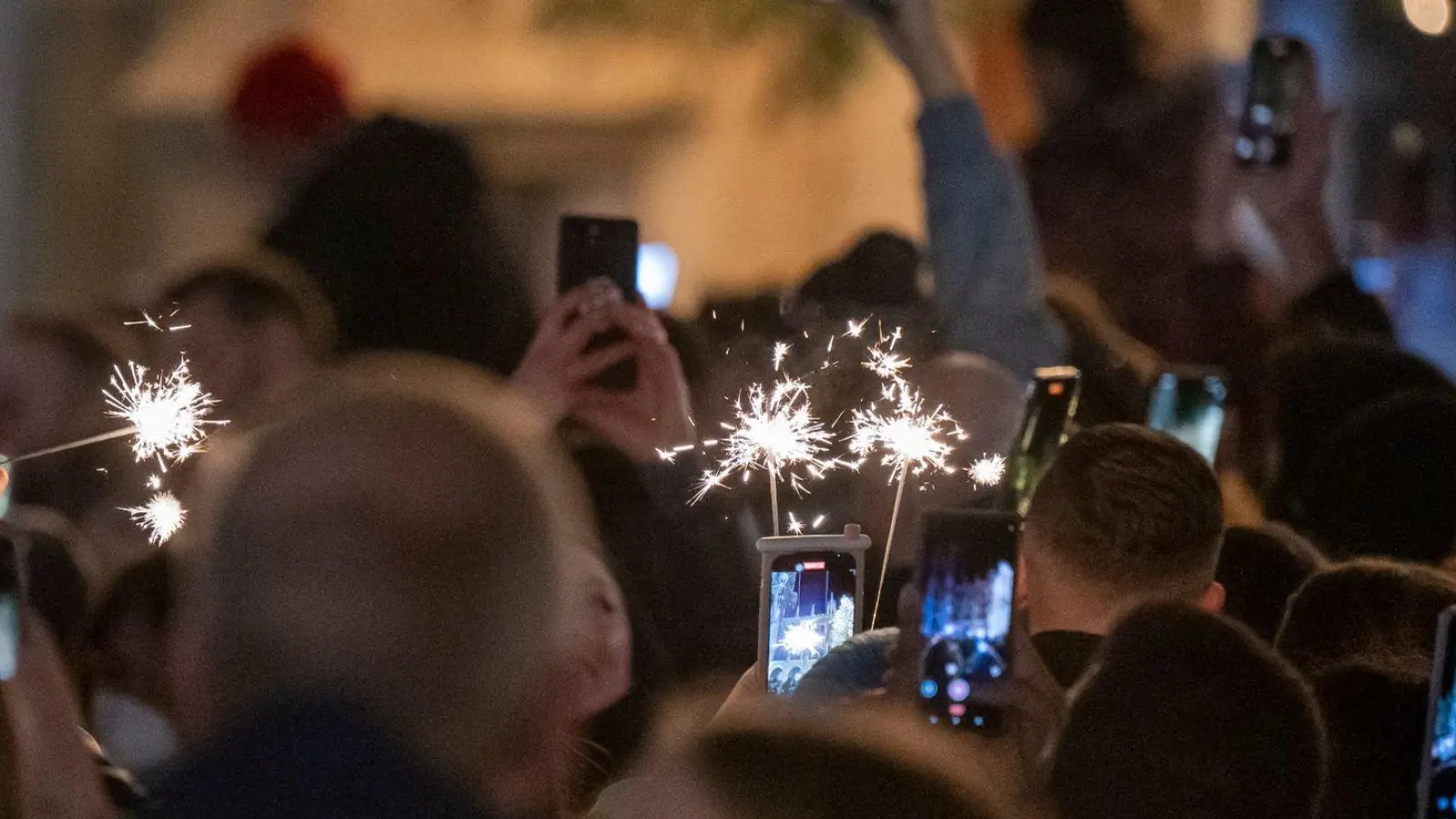 Menschen machen Fotos mit ihren Smartphones, während sie den Jahreswechsel feiern. (Foto: Peter Kneffel/dpa)