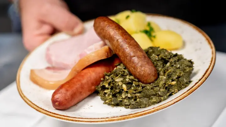 Grünkohl mit den traditionellen Beilagen Salzkartoffeln, Kochwurst, Pinkelwurst und Kasseler wird im Restaurant „Bümmersteder Krug“ serviert. (Foto: Hauke-Christian Dittrich/dpa)