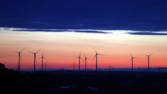 Windräder stehen unter einer Wolkenwand im Sonnenaufgang. (Foto: Karl-Josef Hildenbrand/dpa)