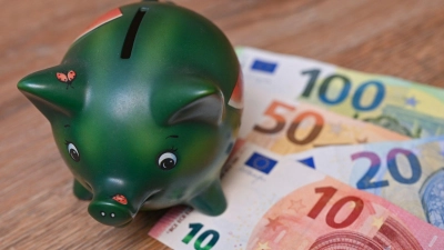 Ein Sparschwein steht auf einem Tisch neben Eurobanknoten. (Foto: Patrick Pleul/dpa-Zentralbild/dpa/Illustration)