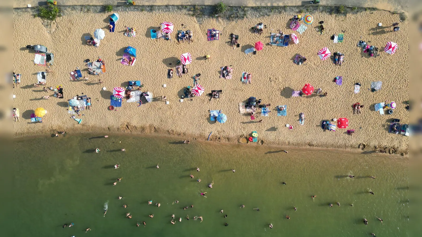 Badegäste liegen am Strand am Rather See in Köln (Luftaufnahmen mit einer Drohne). (Foto: Sascha Thelen/dpa)