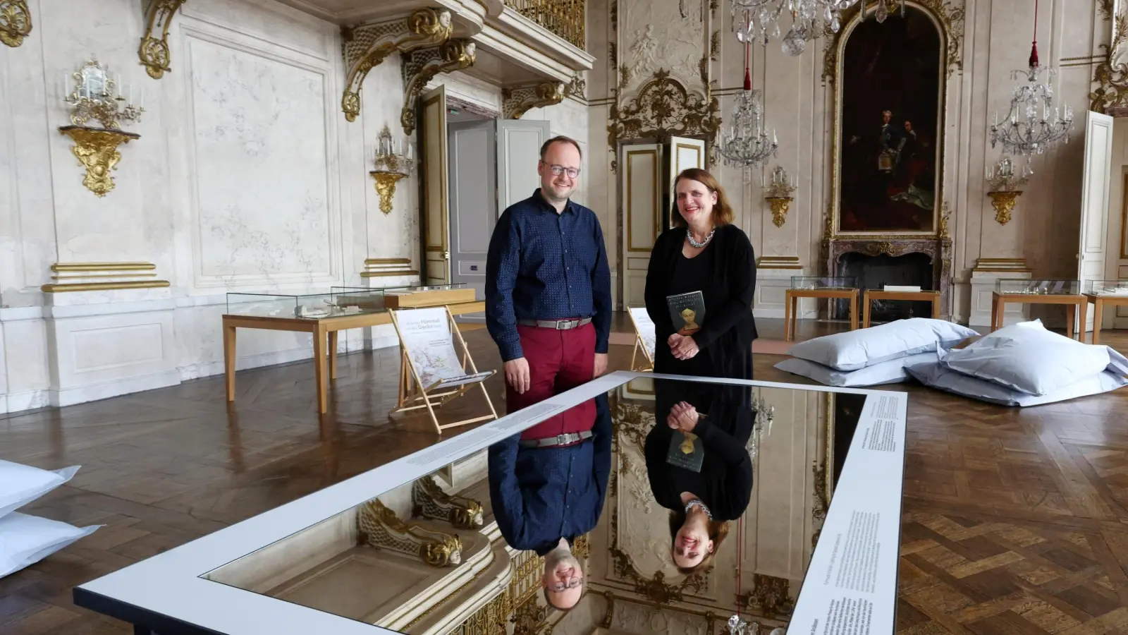 Freuen sich aufs erste „Silent Reading”: Michael Rotschedl, Amtsvorstand der Schloss- und Gartenverwaltung Ansbach, und Bettina Baumann, Vorsitzende des Vereins Wortkunst, im Festsaal der Ansbacher Residenz. (Foto: Thomas Wirth)