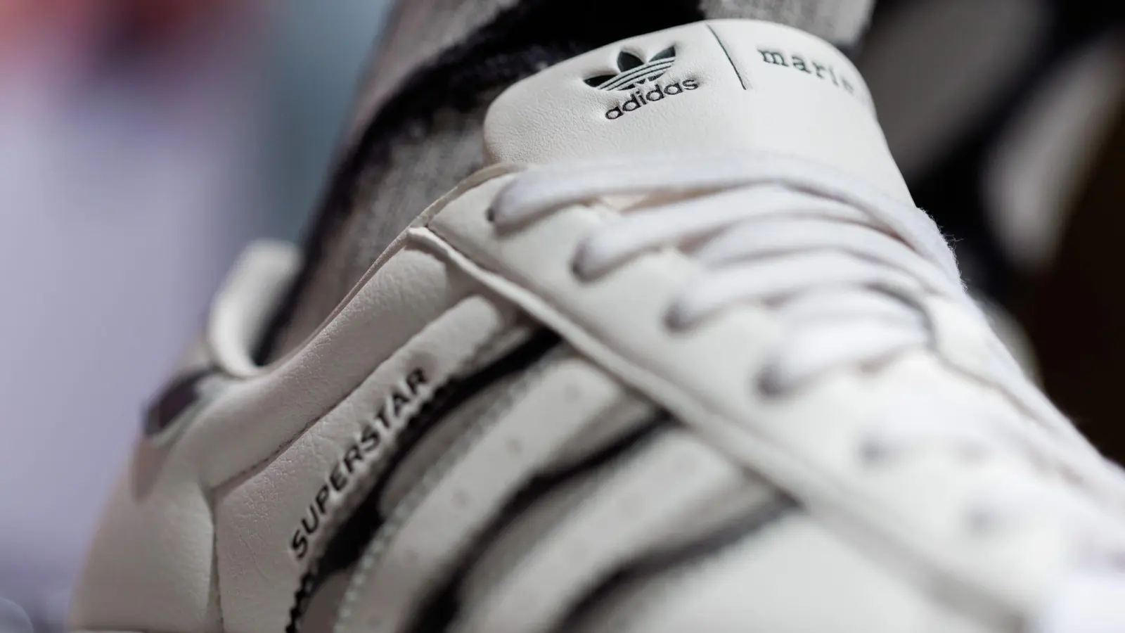 Das Logo und der Schriftzug des Sportartikelherstellers Adidas: Das Unternehmen hat seine neuesten Zahlen vorgelegt. (Foto: Daniel Karmann/dpa)