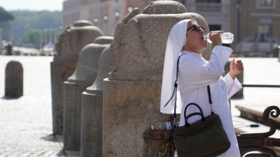 Eine Nonne erfrischt sich auf dem Petersplatz mit einem Schluck aus der Wasserflasche. (Foto: Gregorio Borgia/AP/dpa)
