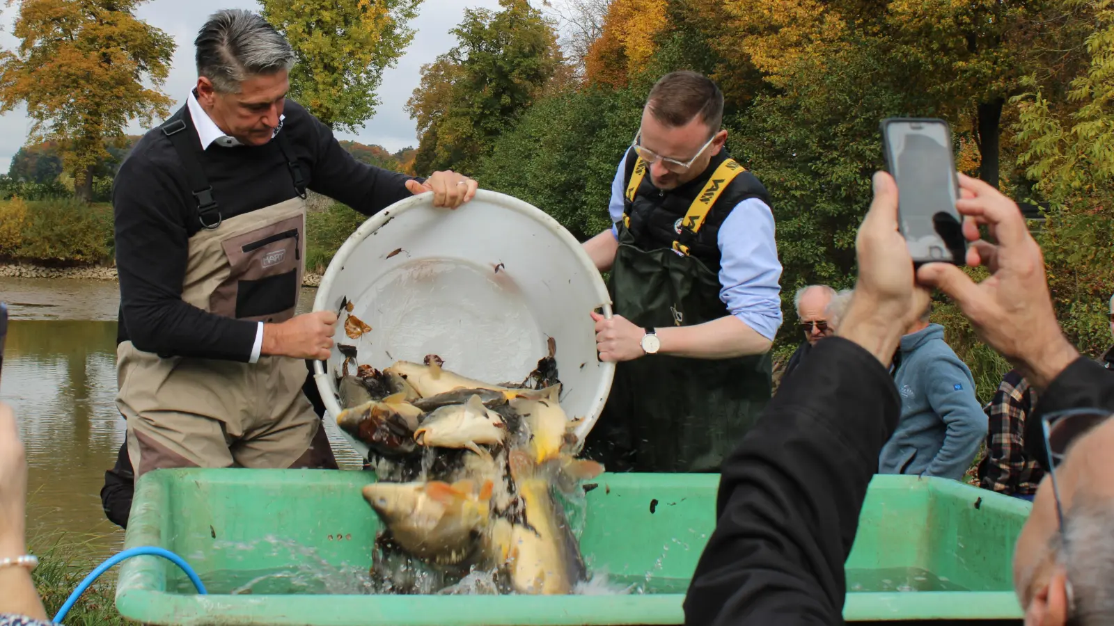 Einige Zuschauende wollten den Moment selbst festhalten, als Peter Bischoff, Leiter der Fischereifachberatung, (links) und Bezirkstagspräsident Peter Daniel Forster ihren Fang präsentierten. (Foto: Constantin Prosch)