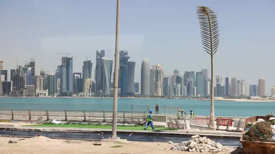 Arbeiter sind auf einer Baustelle an der Promenade Corniche mit Blick auf die Skyline von West Bay Doha zu sehen. (Foto: Christian Charisius/dpa)