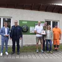 Landrat Marco Meier, Bürgermeister Michael Dörr, Sebastian Klostermeier, Thomas Hubinger, Michaela Botz vom Förderverein und Harald Zeller vom Bauhof (von links) freuten sich, dass ein weiterer Defibrillator-Standort am alten Kindergarten aufgestellt werden konnte. (Foto: Christina Özbek)