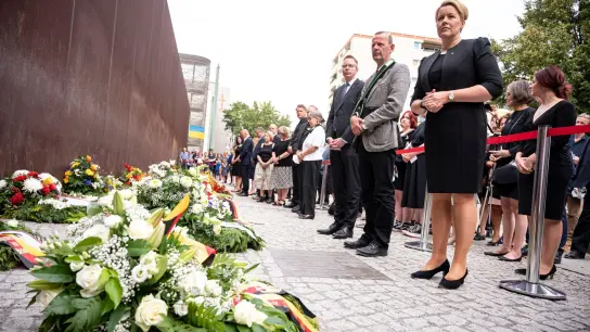 Franziska Giffey (SPD,r), Regierende Bürgermeisterin von Berlin, steht bei der Gedenkveranstaltung für die Opfer von Mauer und Teilung vor den Gedenkkranz vor dem Mahnmal. (Foto: Fabian Sommer/dpa)
