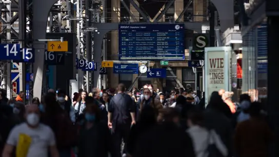 Reisende gehen durch die Bahnhofshalle in Frankfurt/Main. Die Debatte um die Maskenpflicht in öffentlichen Transportmitteln geht weiter. (Foto: Hannes Albert/dpa)