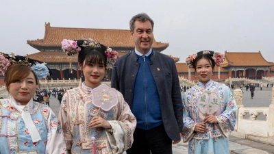 Markus Söder besucht die historische verbotene Stadt in der chinesischen Hauptstadt und steht neben Frauen in traditionellen Kostümen. (Foto: Peter Kneffel/dpa)