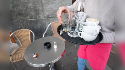 Eine Servicekraft räumt die Tische in einem Café ab. (Foto: Sebastian Gollnow/dpa/Symbolbild)