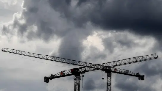 Baukräne vor dunklen Wolken. Fachleuten zufolge wird Deutschland im kommenden Jahr in die Rezession rutschen. (Foto: Britta Pedersen/dpa-Zentralbild/dpa)