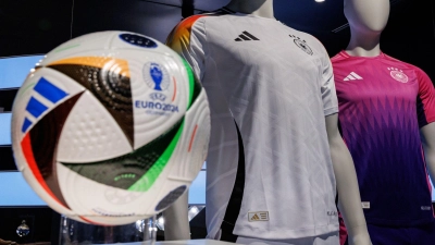 Die offiziellen Trikots der deutschen Fußball-Nationalmannschaft für die kommende Fußball-Europameisterschaft 2024 (UEFA EURO 2024) und der offizielle Spielball sind am Sitz des Sportartikelherstellers adidas AG zu sehen. (Foto: Daniel Karmann/dpa)