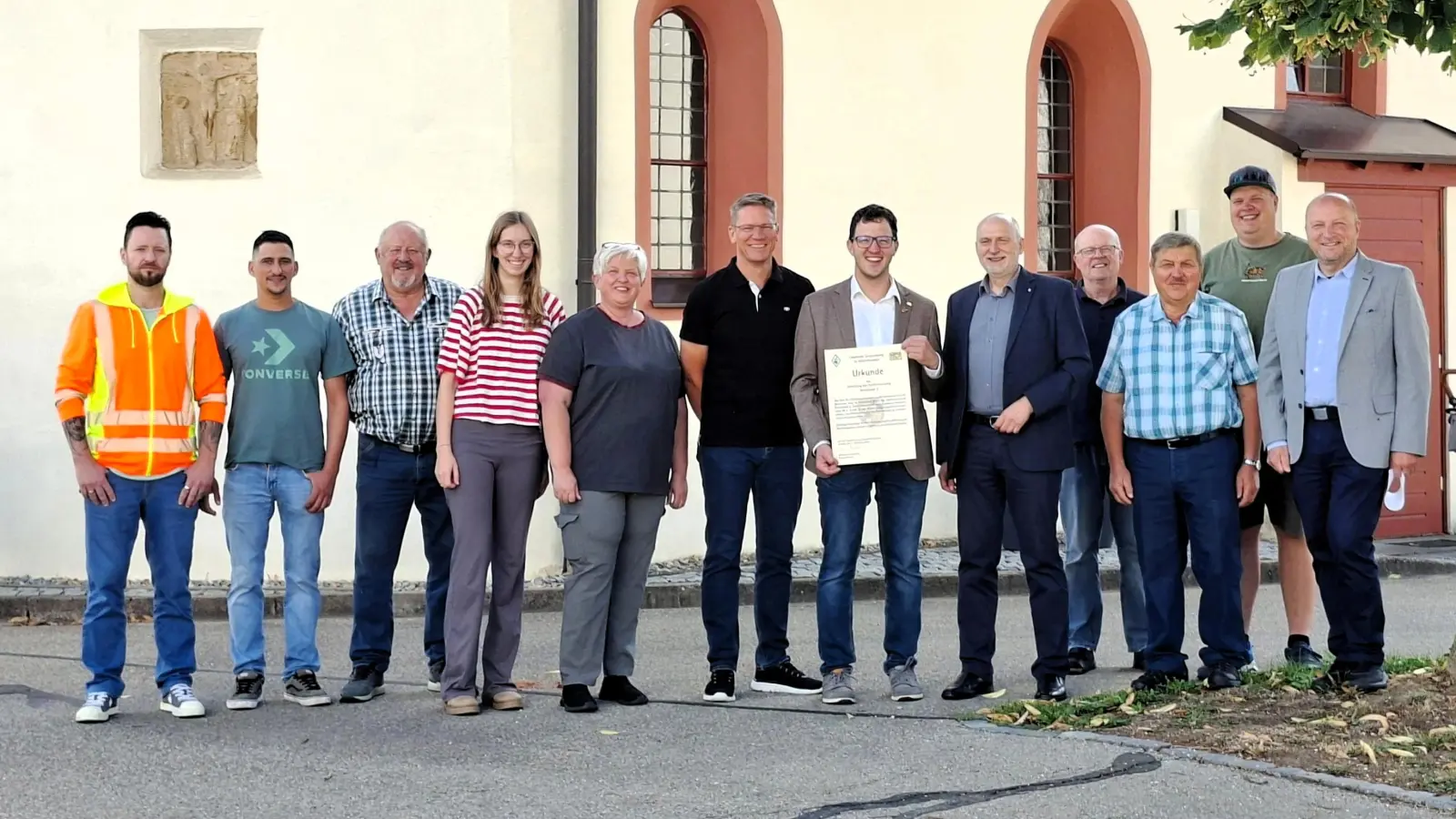 Wassertrüdingens Bürgermeister Jörg Edelmann (Mitte, mit Urkunde) freut sich gemeinsam mit Ingo Steinbrecher (Abteilungsleiter am Amt für Ländliche Entwicklung Mittelfranken, rechts daneben) und Projektleiter Jens Schulze (rechts) über den offiziellen Startschuss zur Dorferneuerung. Mit dabei waren auch engagierte Anwohner und Mitglieder der Arbeitskreise. (Foto: ALE/Diane Mayer)