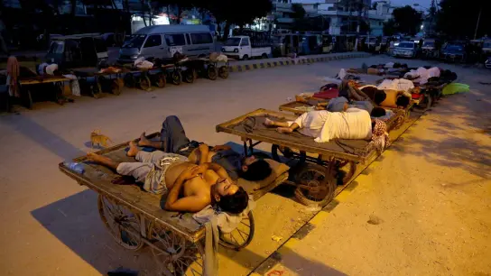 Verkäufer und Rikscha-Fahrer schlafen an einem heißen Sommermorgen im Freien. (Foto: Fareed Khan/AP/dpa)