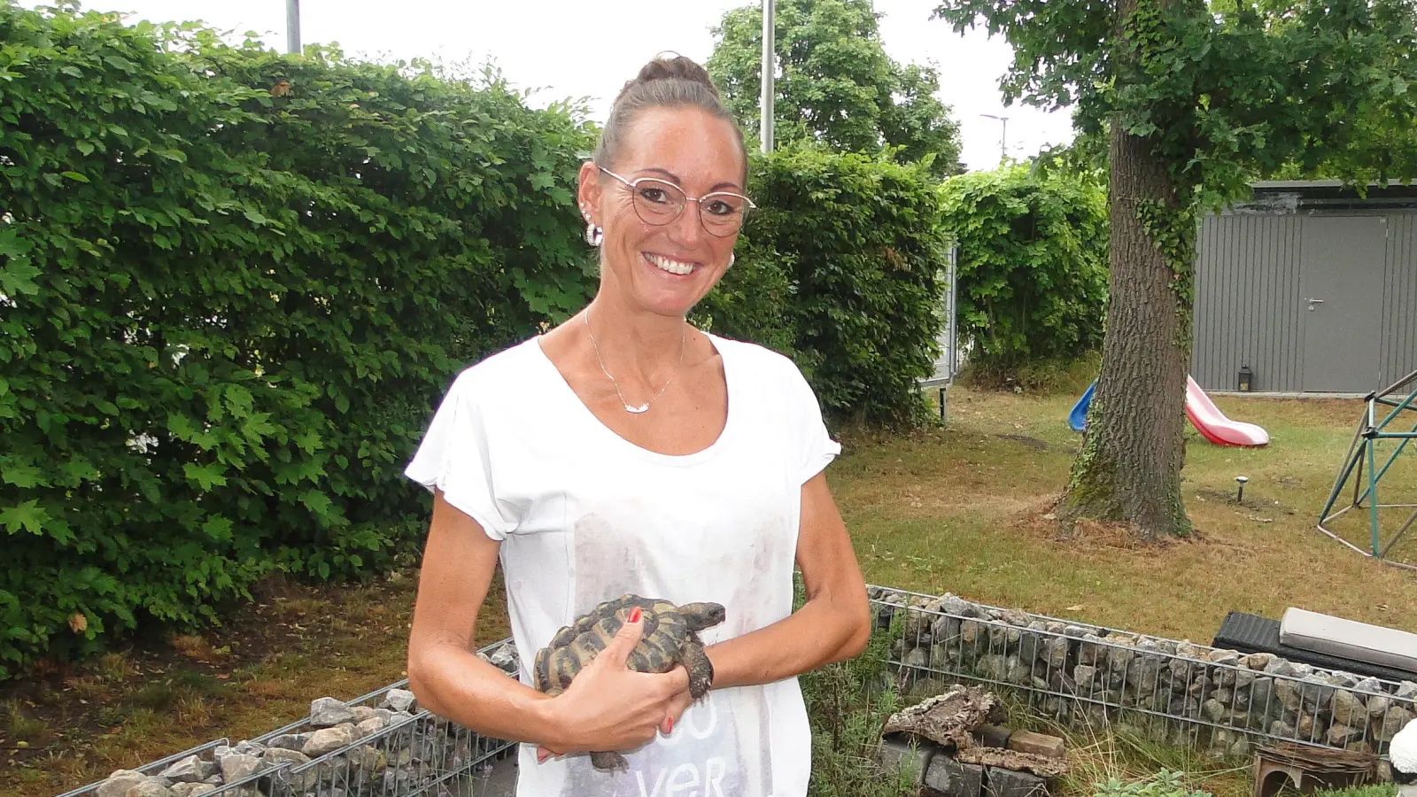 Pension für gepanzerte Gäste: Linda Carl steht mit Fund-Schildkröte Ali auf dem Arm im selbstgebauten Gehege. (Foto: Winfried Vennemann)