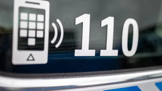 Der Nummer des Polizeinotrufs 110 steht auf der Scheibe eines Polizeifahrzeugs. (Foto: Daniel Karmann/dpa/Symbolbild)