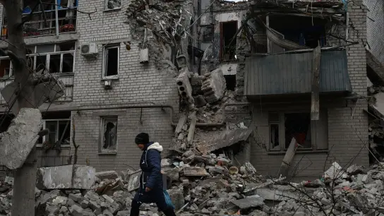 Eine Frau geht an den Trümmern eines zerstörten Hauses nach einem Luftangriff vorbei. (Foto: Andriy Andriyenko/AP/dpa)