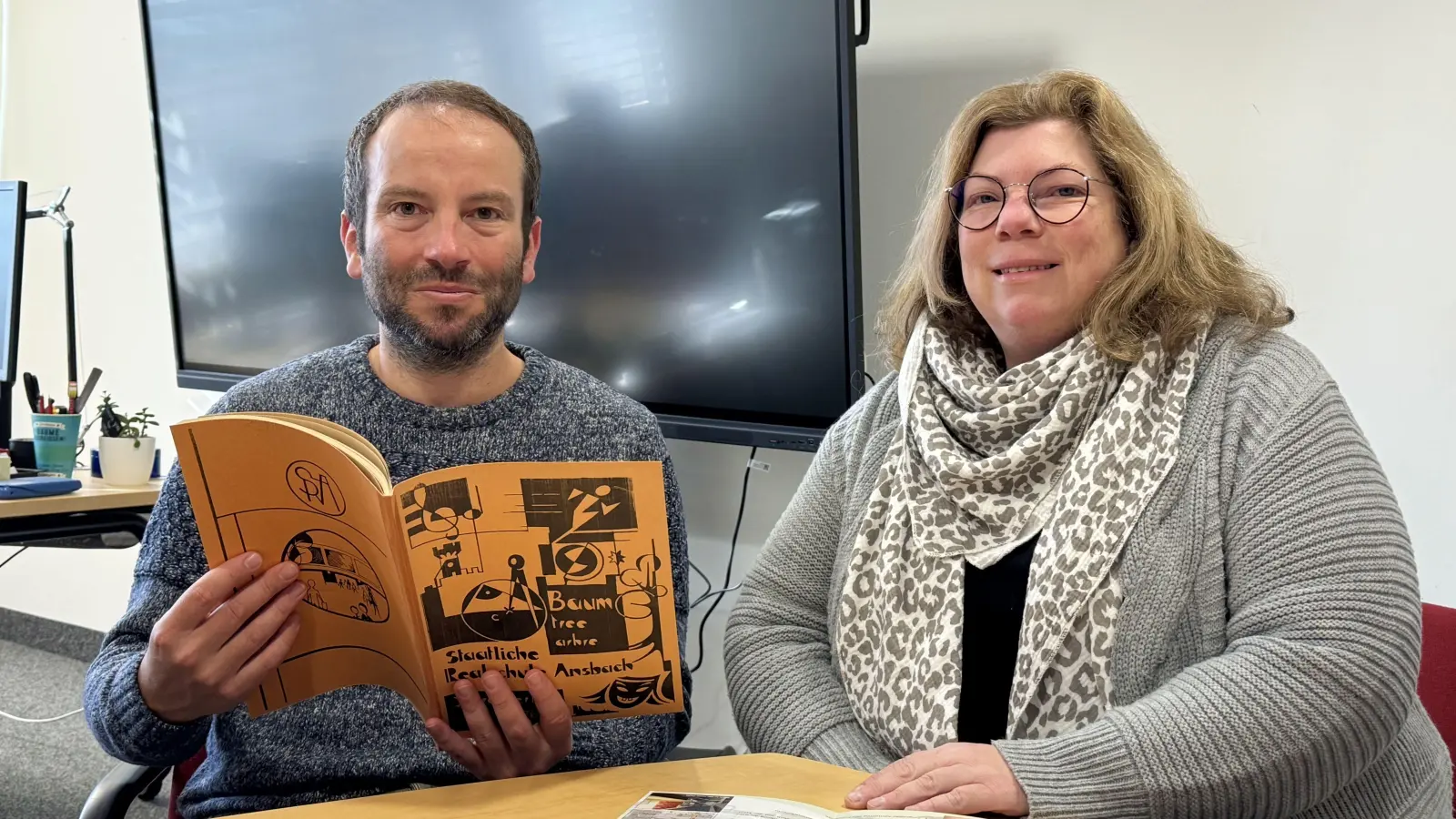 Realschuldirektor Thomas Häckel, hier mit Beratungsrektorin Nicole Blakert, blättert zum Jubiläum in einem alten Jahresbericht. (Foto: Oliver Herbst)