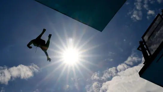 Ein Mann springt im Freibad vom Zehn-Meter-Turm. (Foto: Oliver Berg/dpa)
