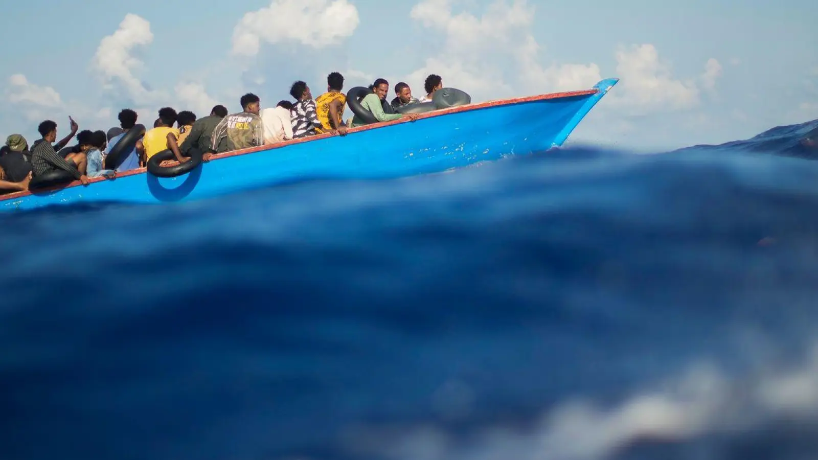 Menschen, die nach Europa wollen, sitzen in einem Holzboot im Mittelmeer. Symbolbild (Foto: Francisco Seco/AP/dpa)