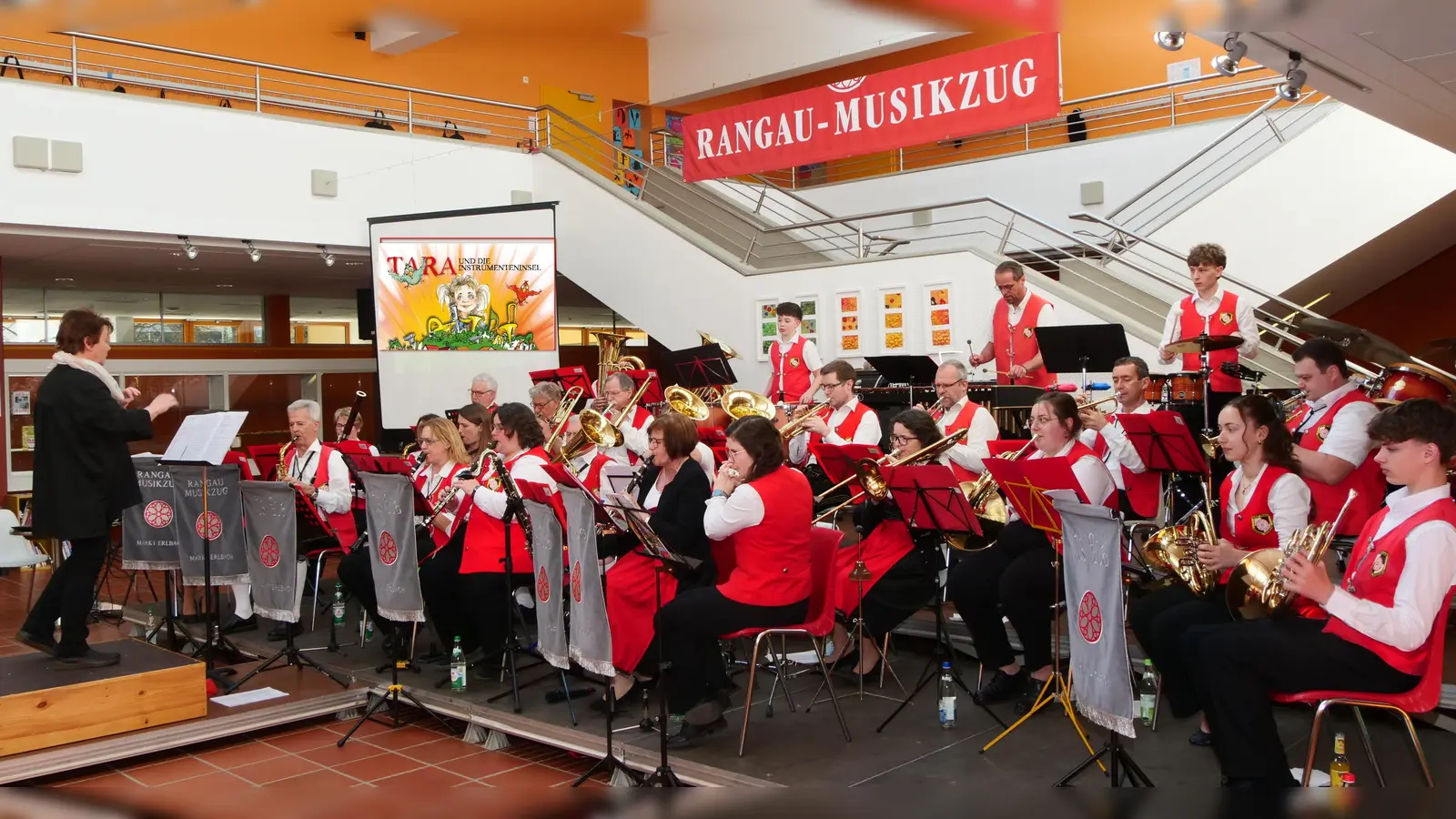 Der Rangau-Musikzug mit Anke Lechner am Dirigentenpult. Im Hintergrund lief eine Videodarbietung der Instrumente als Zeichentrick.  (Foto: Markus Steinbach)