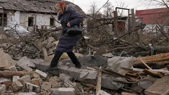 Eine Frau steigt in Kiew über Trümmer von Gebäuden. (Foto: -/kyodo/dpa)