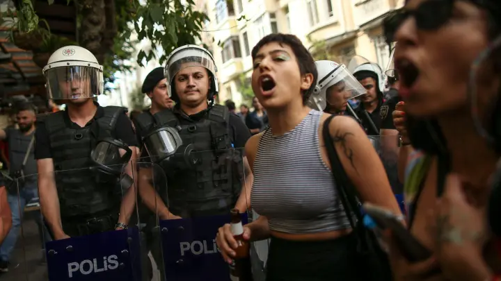 Teilnehmende der Pride-Parade in Istanbul stehen neben Polizisten und rufen Slogans. (Foto: Emrah Gurel/AP/dpa)