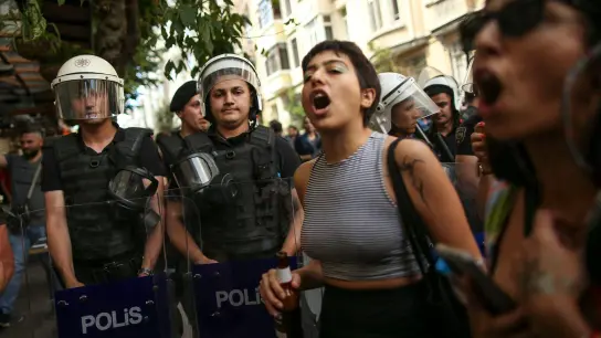 Teilnehmende der Pride-Parade in Istanbul stehen neben Polizisten und rufen Slogans. (Foto: Emrah Gurel/AP/dpa)