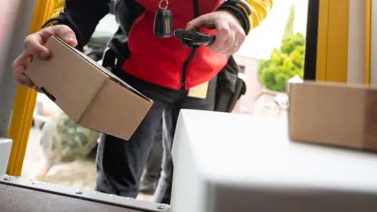 Ein DHL-Mitarbeiter scant ein Paket für die Zustellung. (Foto: Sebastian Gollnow/dpa)