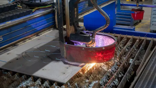Eine Maschine schneidet bei einem Maschinenbauer aus Stahlplatten Werkstücke. Zunehmende Handelsbarrieren erschweren die Geschäfte europäischer Maschinen- und Anlagenbauer außerhalb der Europäischen Union. (Foto: Stefan Puchner/dpa)